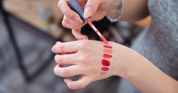 woman testing lip-gloss samples on the back of her hand