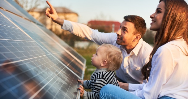 Young family looking at solar panels at sunset