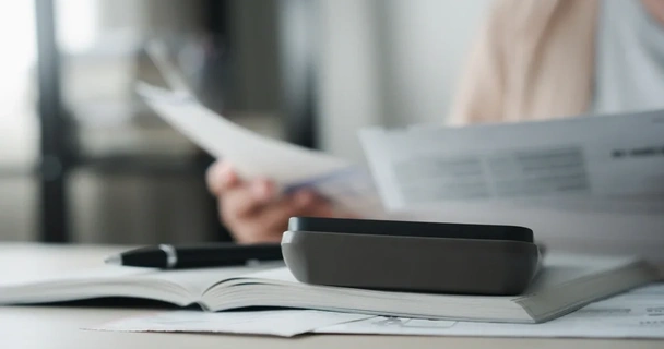 close up of someone looking through documents with a pen and calculator