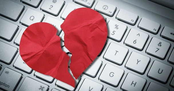 Red paper heart torn on top of a computer keyboard