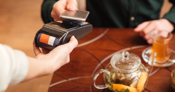 Person paying contactless using their phone on a card machine.