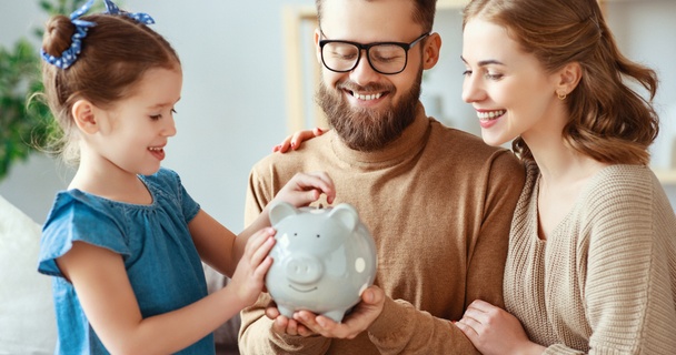Family putting money away into piggy bank