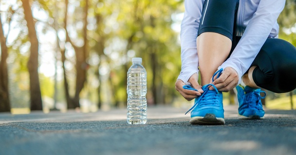 Female runner tying her laces next to a bottle of water