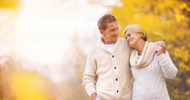 An elderly couple taking a walk in a forest in autumn