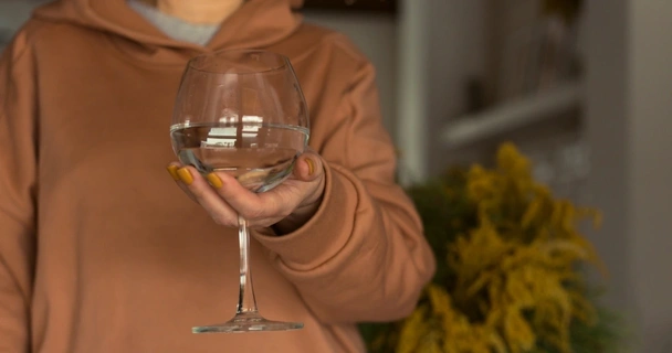 Woman holding wine glass of water