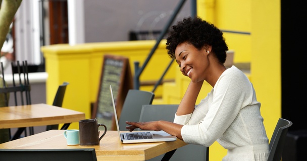 Happy woman using laptop at outdoor coffee shop