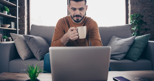 man on laptop at home drinking tea