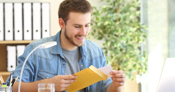 smiling man at desk with envelopes