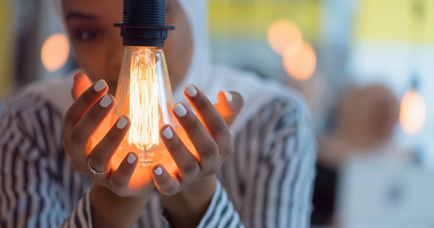 A lady cups her hands round a designer lightbulb