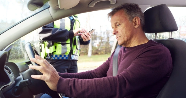 A man in his car with a police officer by his window