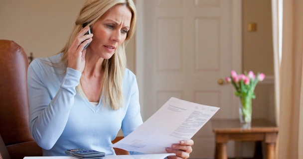 concerned woman looking at bills and talking on her mobile