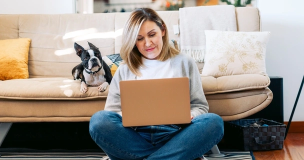 woman sat on floor with laptop and dog