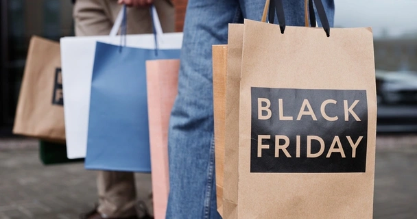 A couple holding shopping bags that say Black Friday on them