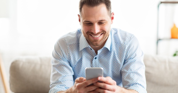 young man smiling while using mobile phone