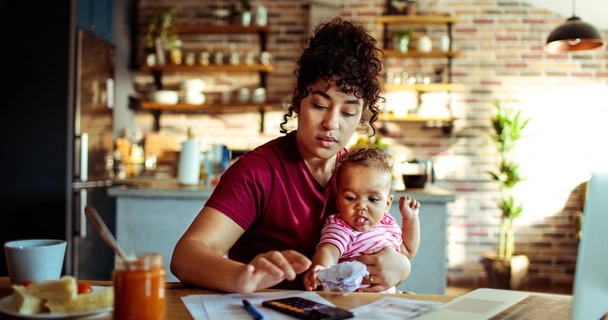 mother sat at desk with baby using a calculator