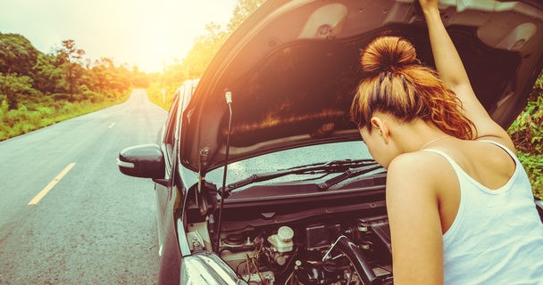 Woman on the side of the road checking engine oil levels of car