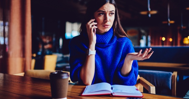 Woman talking on the phone at a table with a coffee cup