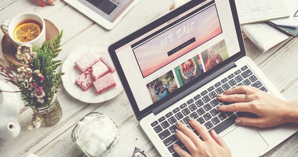 Woman online shopping on her laptop with a friend