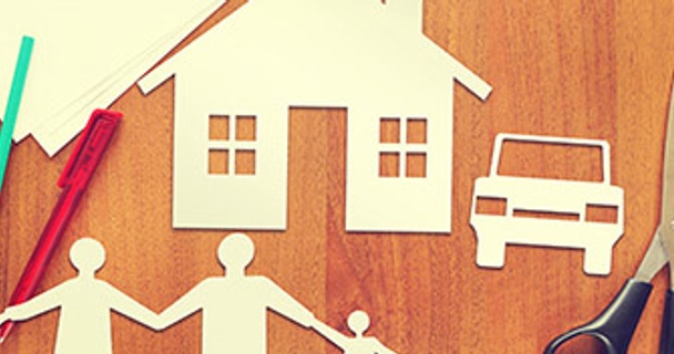 Paper cut out of a family holding hands and a house with a car