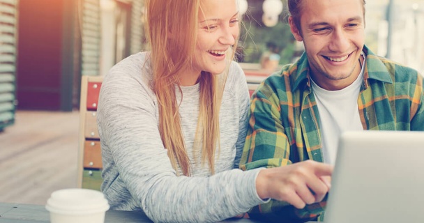Happy couple looking and pointing at laptop screen