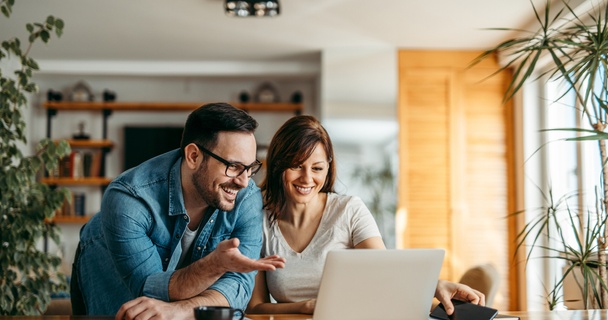 couple at a laptop looking surprised and happy