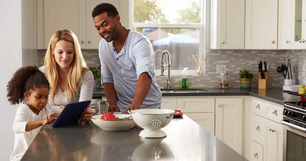 A family looking at a tablet on a kitchen counter