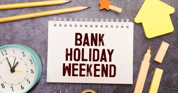 Bank holiday weekend written on paper with sticky notes and pencils next to it.