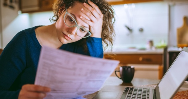 Woman looking at a bill with a stressed expression