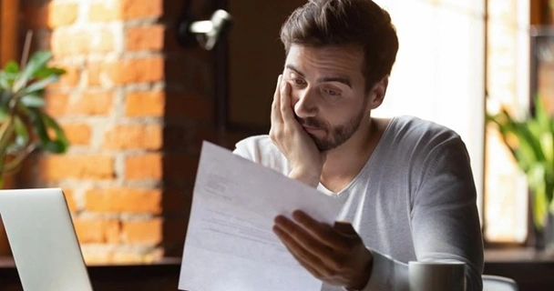 a man looking glumly at his bill