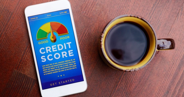 Mobile phone with a credit score meter on the screen, by a cup of coffee