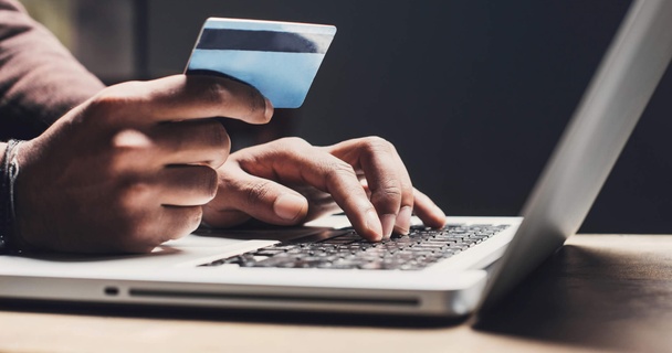 Person holding a credit card while browsing on a laptop