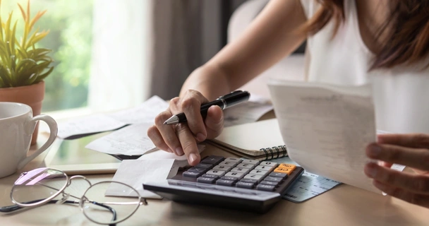 Woman sat at the table with receipts and a calculator