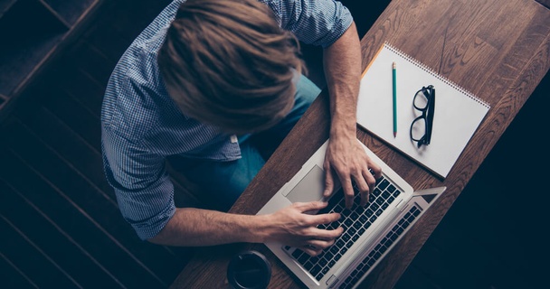 Birds eye view of a man sat at his laptop.