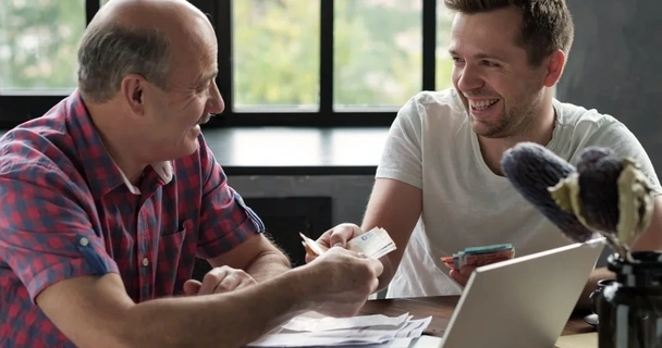 two men smiling and exchanging cash