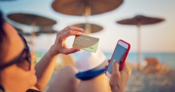 Lady on a beach with a credit card in hand