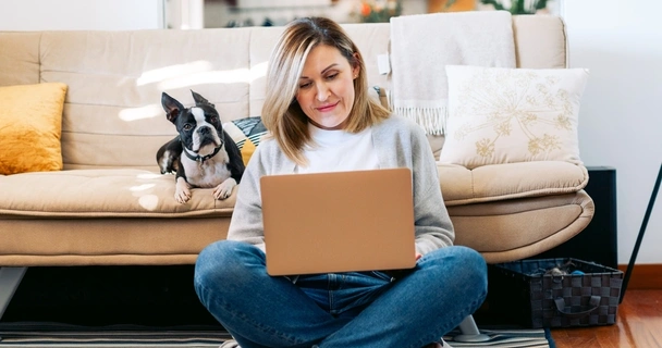 woman sat on floor with laptop and dog