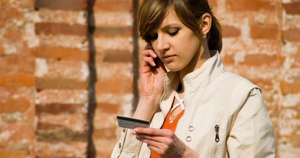 woman on the phone holding a credit card