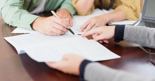 Someone signing a document in front of a witness