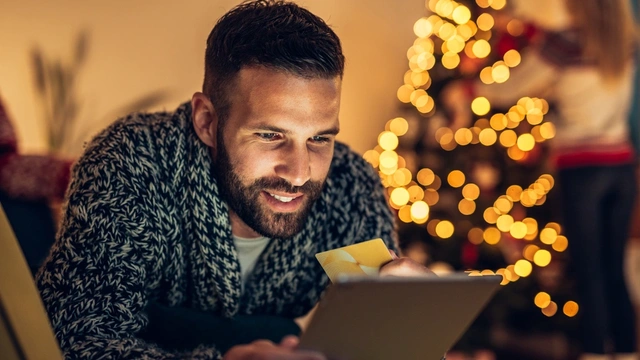 Man online shopping with a Christmas jumper on