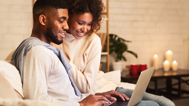 Happy Black couple using laptop
