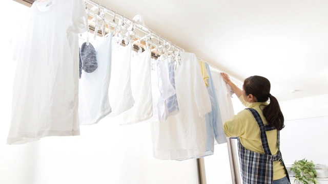 woman hanging up clothes to dry on curtain rail