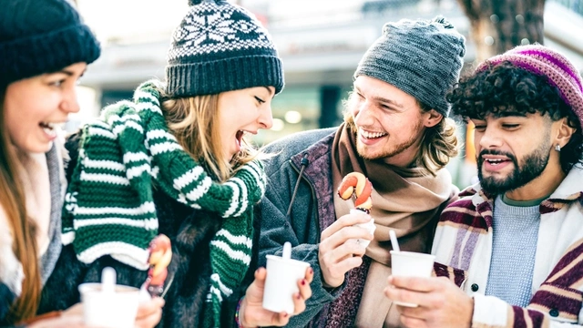 Group of friends talking and drinking coffee outdoors during winter