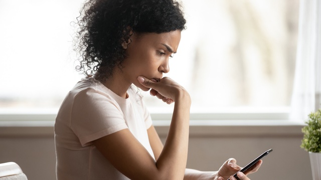 worried woman looking at mobile phone