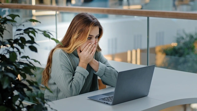 woman looking shocked on laptop