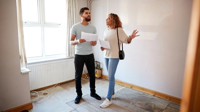 Couple looking at a house survey in a room to be renovated