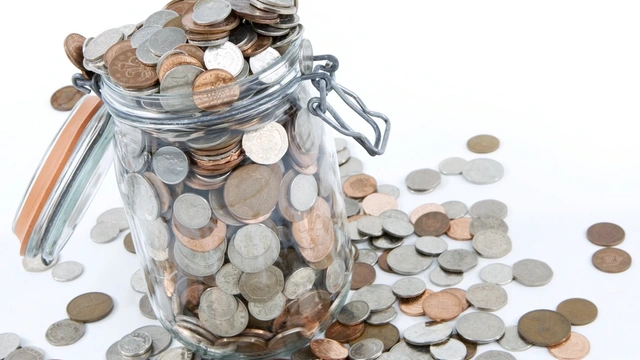 Mason jar with a variety of British coins on a white background