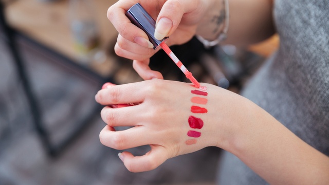 woman testing lip-gloss samples on the back of her hand