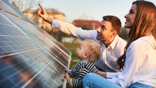 Young family looking at solar panels at sunset