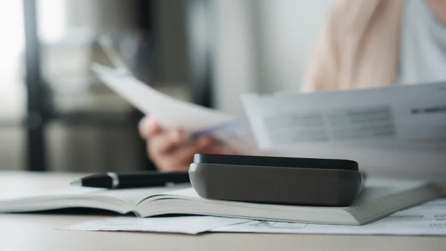 close up of someone looking through documents with a pen and calculator