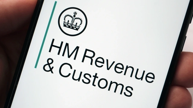 Hand holding a mobile phone with HM Revenue & Customs on the screen
